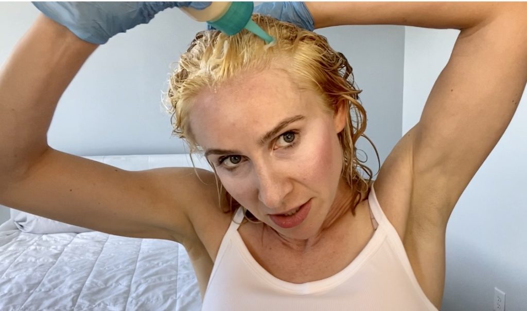 blond girl applying Wella T28 toner to her hair to go blonde while dying her hair at home