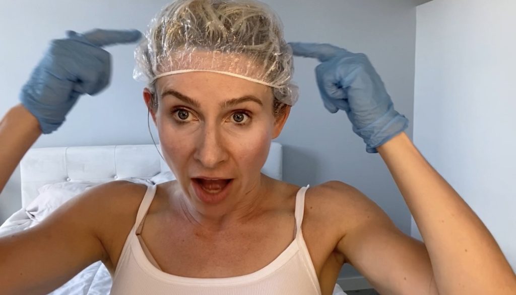 girl with a shower cap on her head after applying bleach to blonde hair at home