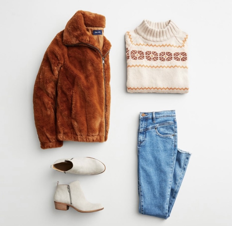 Stitch Fix winter outfit with puffy brown jacket, holiday sweater, jeans, and white booties