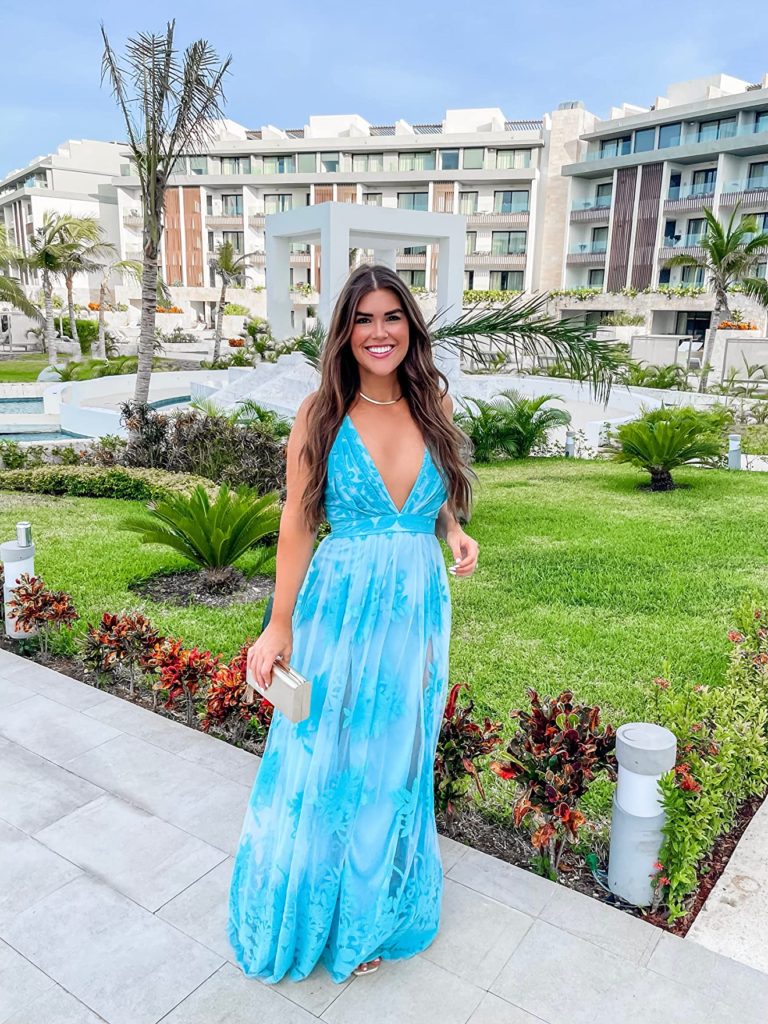 beach wedding guest outfit with blue maxi dress, gold sandals, and gold clutch for wedding guests