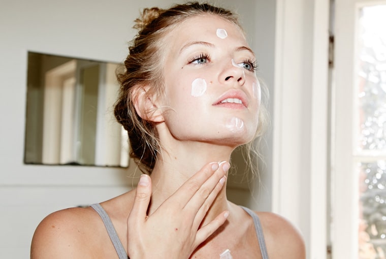 girl putting sunblock on her neck to look younger than her age