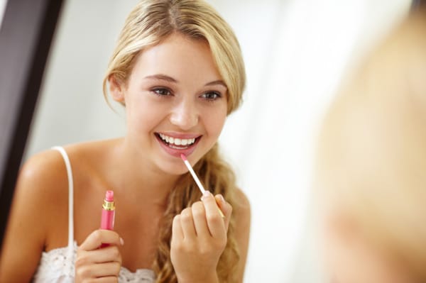 woman applying lip gloss to look younger on Zoom calls