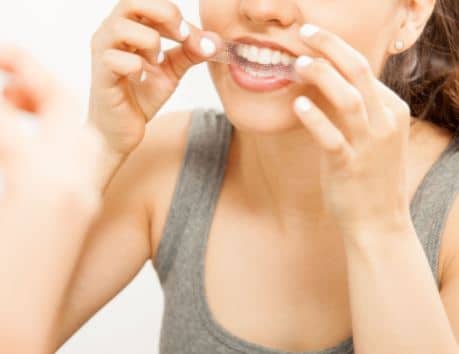 woman whitening her teeth to look younger naturally