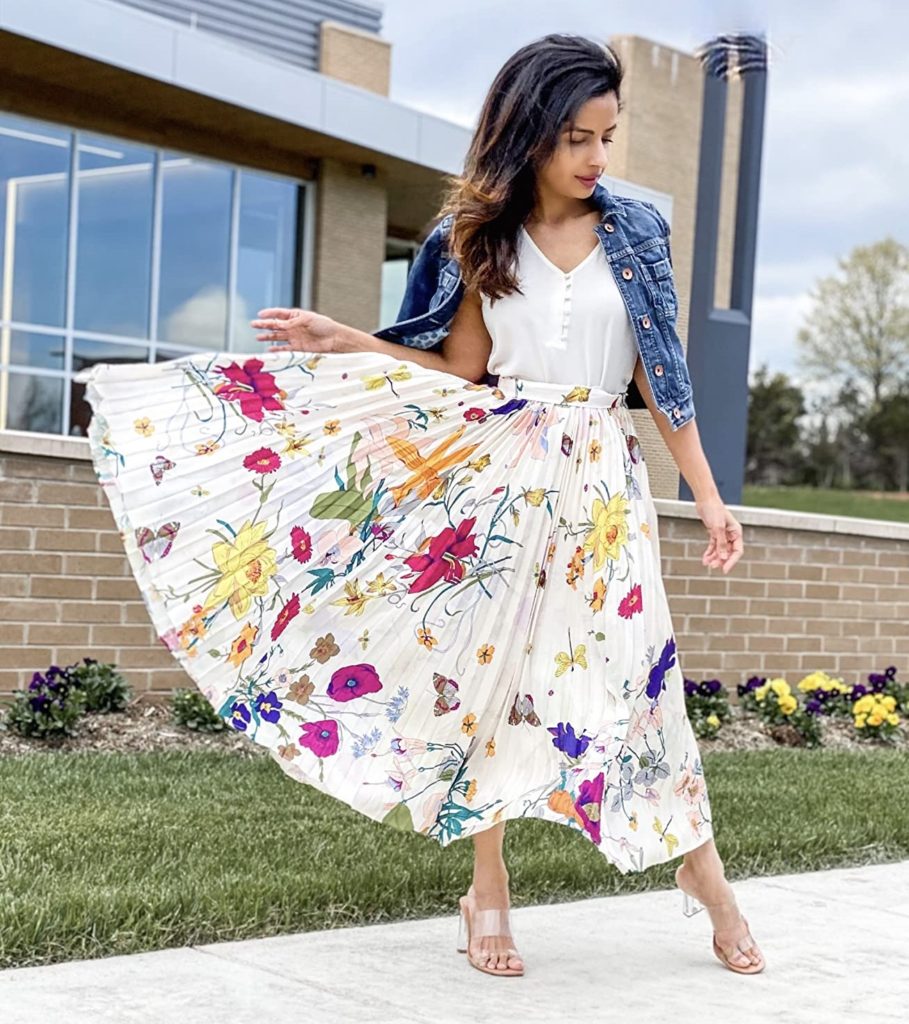 flirty and feminine summer outfit idea with floral pleated skirt, jean jacket, white blouse, and nude sandals