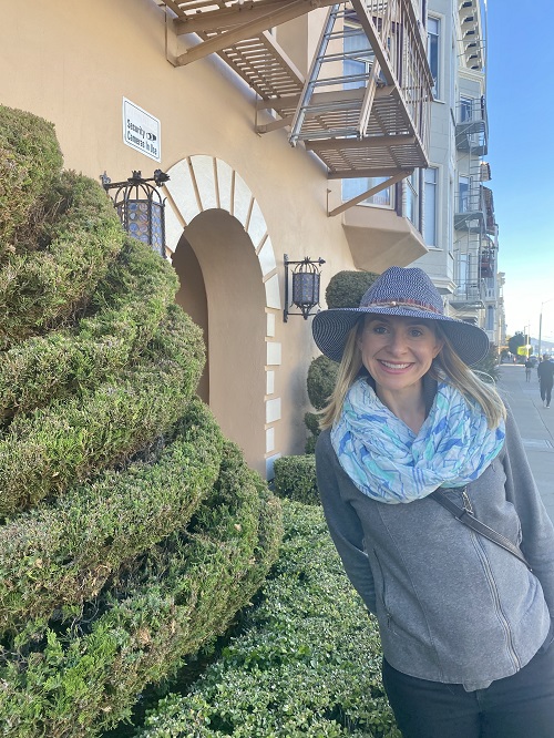 girl in a hat, scarf, sweater, jeans, and jacket for a day trip to San Francisco by Very Easy Makeup