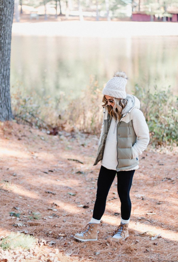 winter outfit with black leggings, a cream jacket, and a white/tan beanie