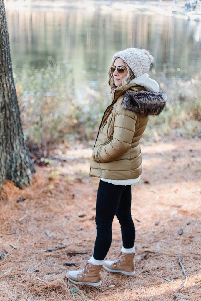 winter outfit with black leggings, a tan puffy jacket, hiking boots, and a beanie hat