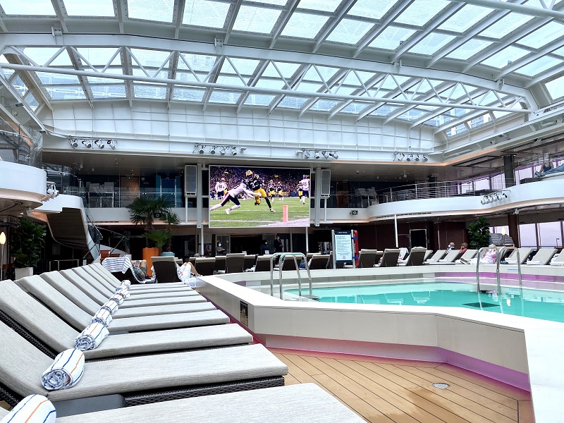 Holland America Rotterdam ship with outdoor pool and football on large outdoor TV