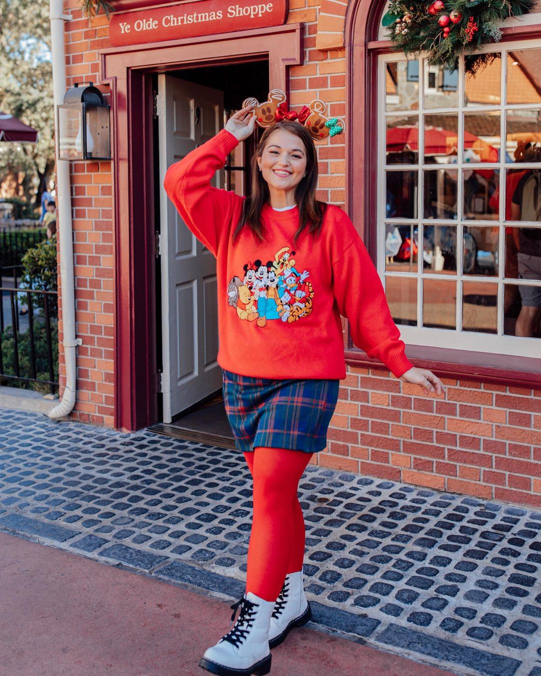 Disney Christmas outfit with red sweatshirt, plaid skirt, and white boots